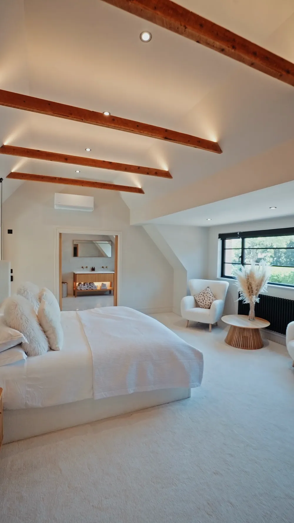 A loft conversion master bedroom with exposed beams and a dormer window