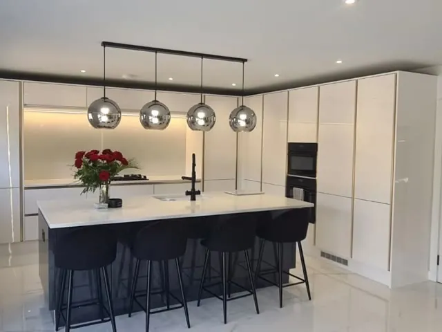 A finished white gloss kitchen with island and pendant lights by Build and Co