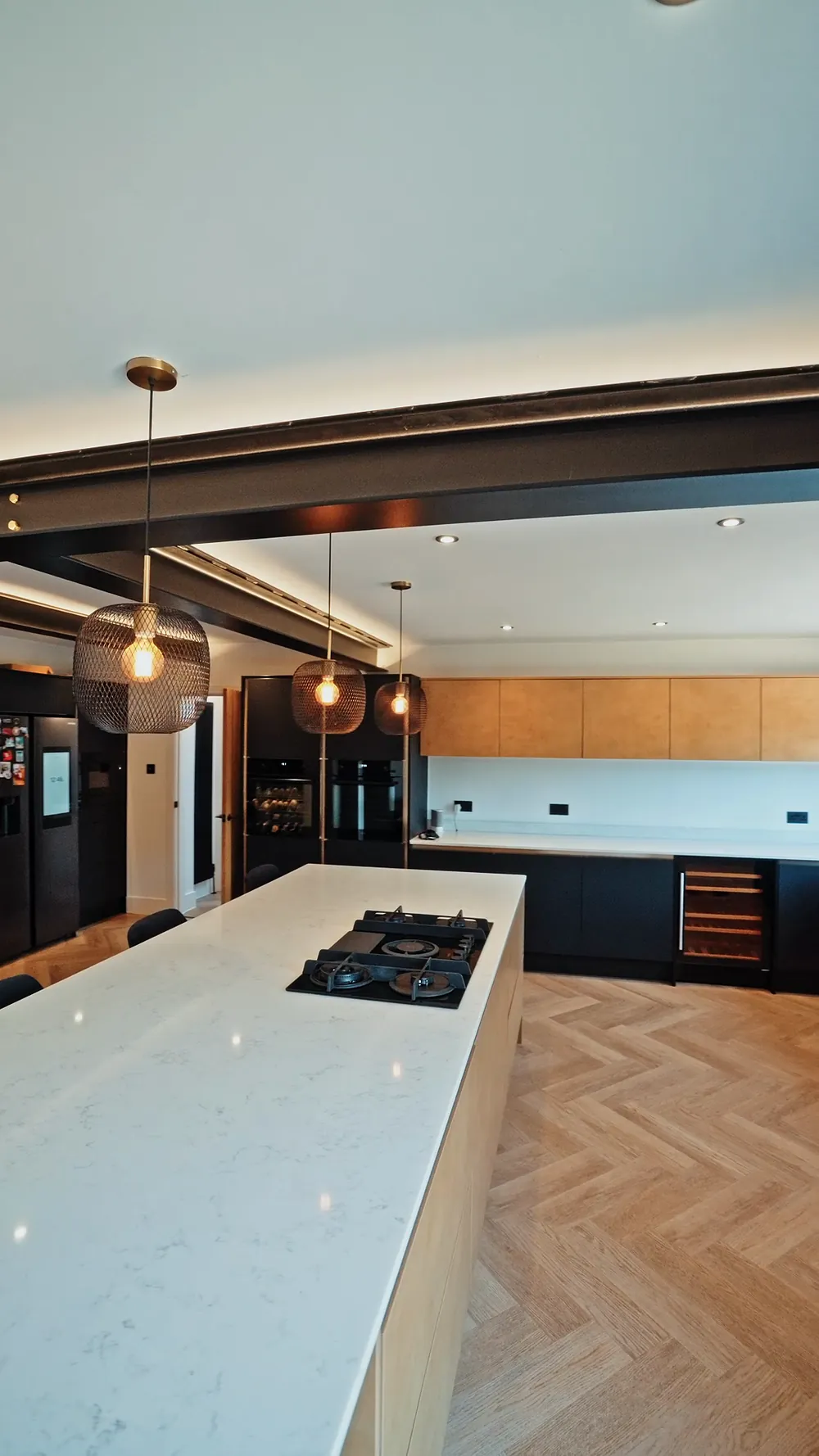 Open plan kitchen island with exposed black steels and herringbone floor